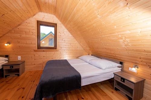 ゴンスキにあるDomki, Apartamenty i Restauracja Włóczęgaの木造キャビン内のベッド1台が備わるベッドルーム1室を利用します。