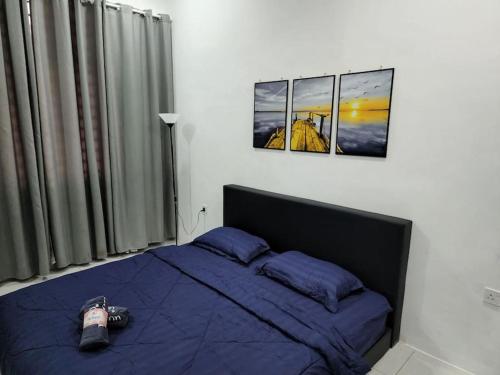 een slaapkamer met een blauw bed met twee foto's aan de muur bij Hud D'Lipis Homestay in Kuala Lipis