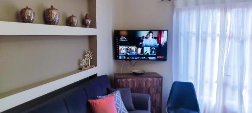 a living room with a blue couch and a tv at ZeusPlace Litochoro Central Traditional House in Litochoro