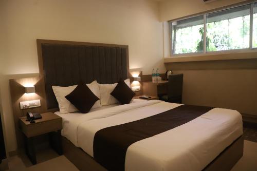 a bedroom with a large bed and a window at Hotel Sai Pritam in Mumbai