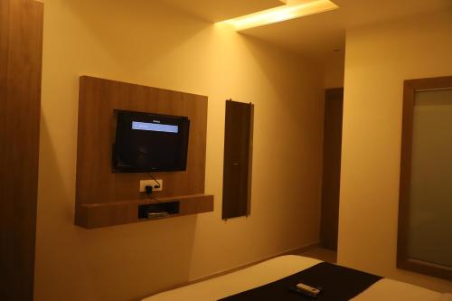 um quarto com uma televisão numa parede com uma cama em Hotel Sai Pritam em Mumbai