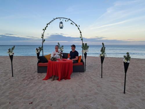 dos personas sentadas en una mesa en la playa en The Tottam Beach Hotel - Trincomalee, en Trincomalee