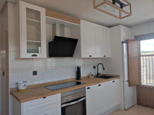 a kitchen with white cabinets and a sink and a tv at La Casa del Valle 2 in Soncillo