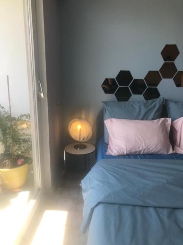 a bedroom with a blue bed and a table with a lamp at Studio Bee Home in De Haan
