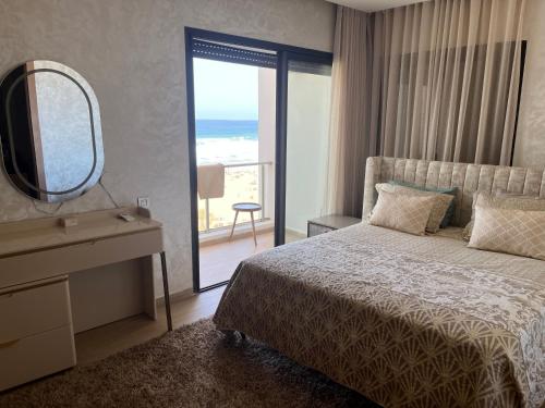 - une chambre avec un lit, un miroir et un balcon dans l'établissement Appartement de luxe, front de mer Plage des nations, à Sale