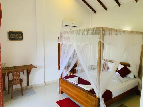 1 dormitorio con cama con dosel y escritorio en Green Hut Hotel & Restaurant, en Sigiriya