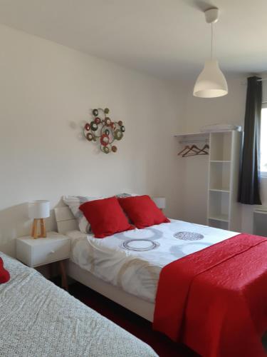 Un dormitorio con una cama con almohadas rojas. en la java, en Saint-Cyran-du-Jambot