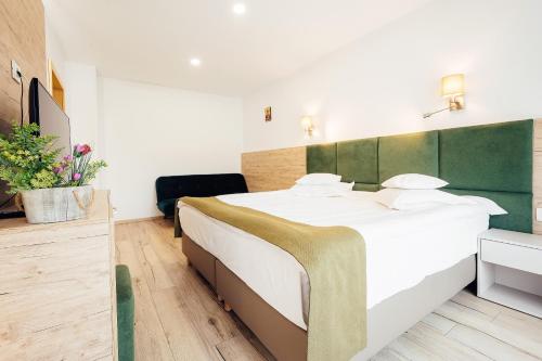 a bedroom with a large white bed with a green headboard at Blumenhof Bucovina in Voronet