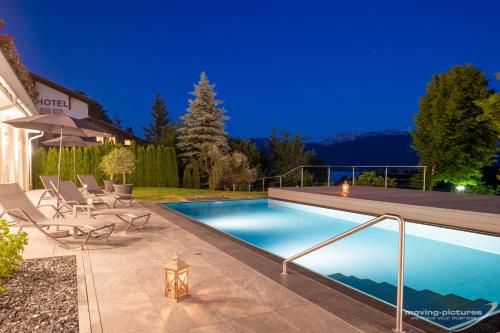 einen Pool im Hinterhof mit Stühlen und einem Sonnenschirm in der Unterkunft Landhotel Schwarzenbach - Wellness & Spa in Rieden