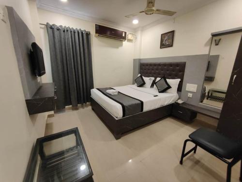 a bedroom with a bed and a chair and a television at HOTEL VIGHNESHWARA INN in Vijayawāda