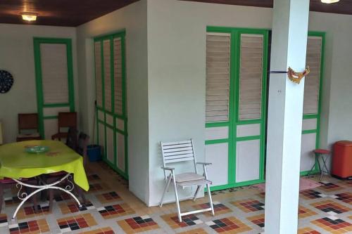 a room with a table and a chair and green doors at Maison spacieuse agréable in Le Morne-Vert