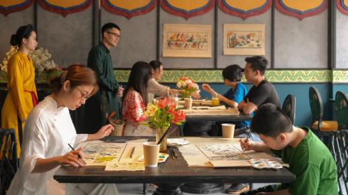 um grupo de pessoas sentadas em mesas em um restaurante em Smarana Hanoi Heritage - Hotel and Retreats em Hanói