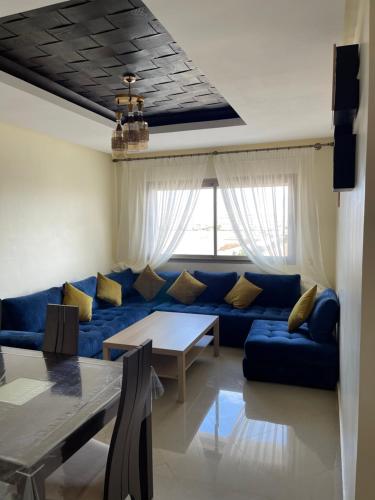 a living room with a blue couch and a table at Superbe Appt avec grande piscine 2 in Dar Bouazza