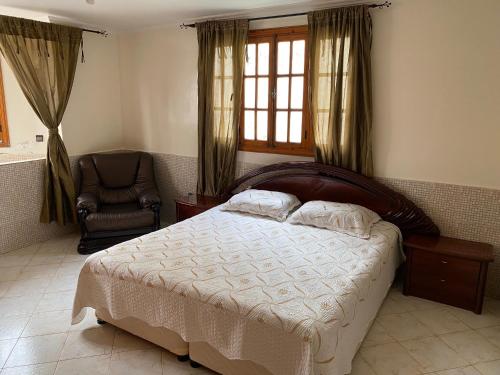 - une chambre avec un grand lit et une chaise dans l'établissement Rez-de-jardin à Mohammedia, à Mohammedia