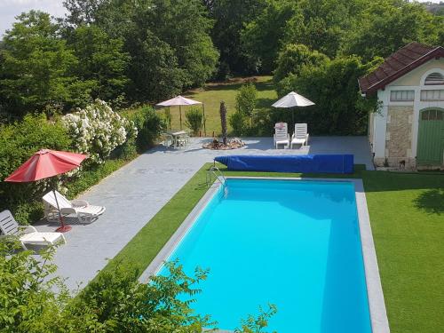 una piscina en un patio con sillas y sombrillas en The Gare Gondrin, en Gondrin