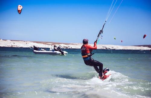 un hombre montando una tabla de cometas en el océano en The Boulders Langebaan en Langebaan