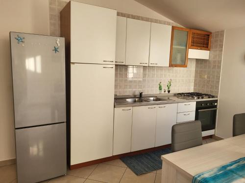 Una cocina con gabinetes blancos y un refrigerador. en IL SOGNO DEL MARE, en Montesilvano