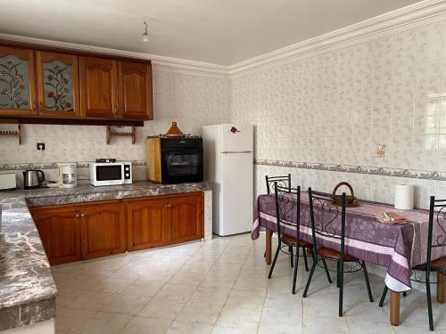 a kitchen with a table and a white refrigerator at Rez-de-jardin à Mohammedia in Mohammedia