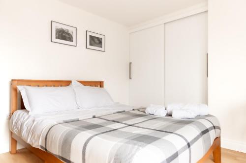 a white bedroom with a large bed with striped sheets at Amethyst Apartment in Oxford