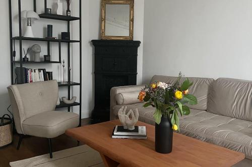 - un salon avec un canapé et une table ornée d'un vase de fleurs dans l'établissement Bel appartement Haussmanien, à Paris