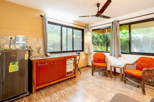 a kitchen with a refrigerator and a table and chairs at The Burrow in South Goa. in Dabolim