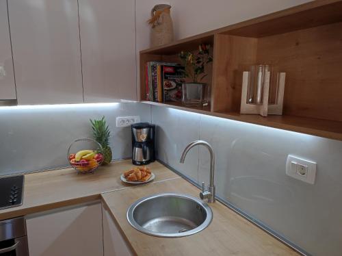 a kitchen with a sink and a bowl of fruit on a counter at Apartman Vlatka 