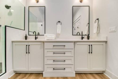 a bathroom with two sinks and two mirrors at Modern Luxury 4BR Pool Bay Access Outdoor Dining in Pensacola