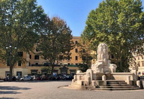 uma estátua em frente a um edifício com carros estacionados em La Maison D'Amelia em Roma