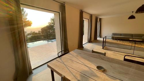 a living room with a wooden table and a large window at Villa Bel Air in Saint-Côme