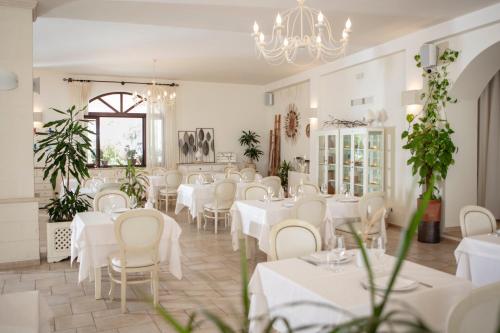a restaurant with white tables and chairs and a chandelier at Borgo Mulino a Vento - Resort in Uggiano la Chiesa