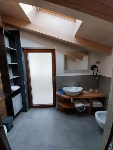 een badkamer met een wastafel, een raam en een deur bij Appartamenti al fiume in Trento