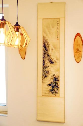 a wall with a picture and two lights and a clock at Alpok – Spirit Apartman Park (Kőszegszerdahely) in Kőszeg