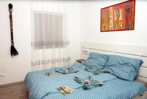a bedroom with a bed with blue sheets and bow pillows at Alpok – Spirit Apartman Park (Kőszegszerdahely) in Kőszeg