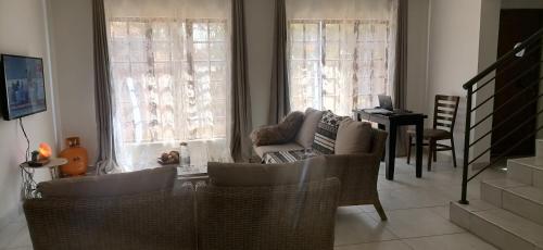 a living room with a couch and chairs and windows at Lady D Exclusive Abode in Polokwane