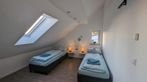 a attic room with two beds and a window at Helle Wohnung mit zwei Schlafzimmern in Eching