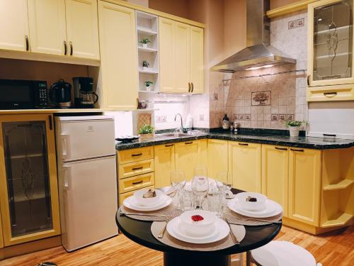 a kitchen with yellow cabinets and a table with dishes on it at Riverside Old Town Spacious One Bedroom Apartment few steps from Dome square and Cathedral in Rīga