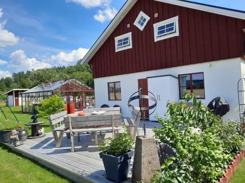 a large red and white house with a wooden deck at Gårdslägenhet nära Göteborg in Alvhem