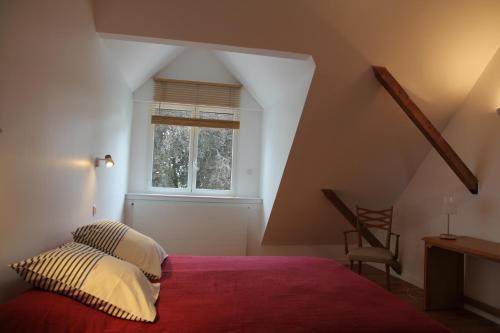 une chambre avec un lit avec une couverture rouge et une fenêtre dans l'établissement la chaumine et ses plages, à Saint-Nazaire