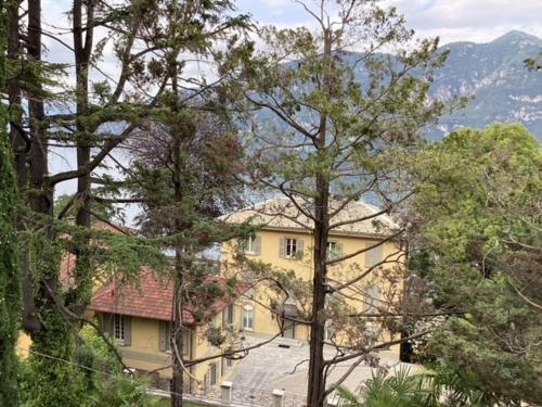 a large yellow house in the middle of trees at wonderful lake front appartment near Bellagio in Limonta