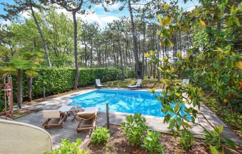 - une piscine avec une table, des chaises et des arbres dans l'établissement Villa Shumann, à Lignano Sabbiadoro