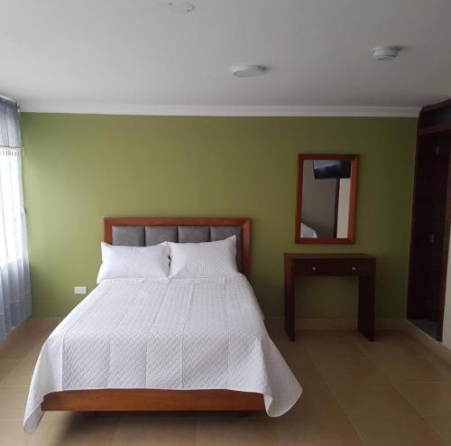 a bedroom with a white bed and a green wall at HOTEL SHANGHAI CITY in Ibarra
