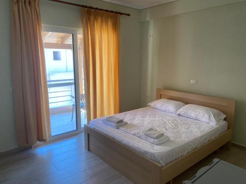 1 dormitorio con 1 cama y puerta a un balcón en Blue Breeze Attic Apartments, en Sarandë