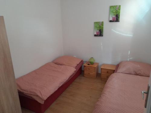 a bedroom with two beds and a wooden floor at Penzión Anika in Krásnohorská Dlhá Lúka