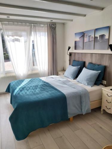 a bedroom with a large bed with blue sheets at Dulce Tierra - vakantiewoning in Zoutelande