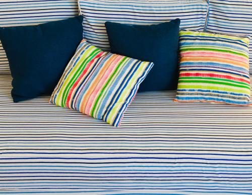 Un sofá con tres almohadas coloridas. en BLUE AND WHITE PAINTERS HOUSE en Atenas