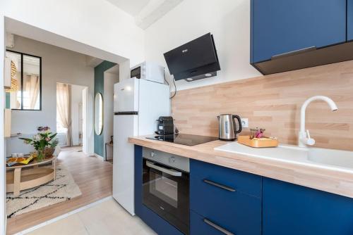eine Küche mit blauen Schränken und einem weißen Kühlschrank in der Unterkunft Ulysse - Charmant T2 dans le Centre de Pont-Audemer in Pont-Audemer