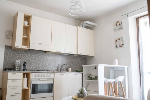 a white kitchen with white cabinets and a table at "Le Charmant" - CIR VDA-SAINT-VINCENT-n 0004 in Saint Vincent