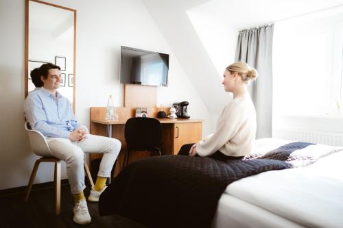 a man and woman sitting in a hotel room at Hotel Rheinpromenade8 in Emmerich