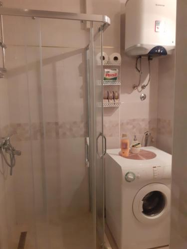 a bathroom with a shower and a washing machine at Apartman Sunce in Podgorica