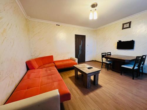 a living room with an orange couch and a table at Apartments NITA in Batumi